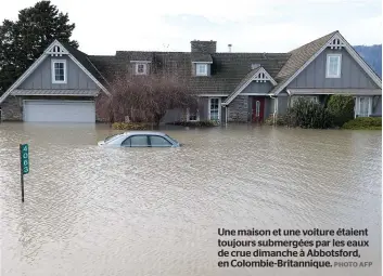  ?? PHOTOAFP ?? Une maison et une voiture étaient toujours submergées par les eaux de crue dimanche à Abbotsford, en Colombie-Britanniqu­e.