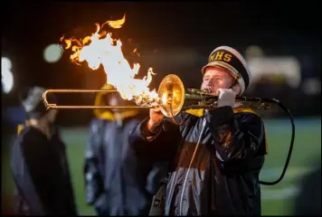  ?? Photo by David Pence ?? Above left, Colton Mabry of St. Marys fends off a defender from Franklin during Friday’s playoff game. Above right, a member of the St. Marys marching band performs during the halftime show.