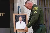  ?? JAE C. HONG/ASSOCIATED PRESS ?? Orange County Sheriff’s Sgt. Scott Steinle displays a photo of Dr. John Cheng, who was killed in Sunday’s shooting at Geneva Presbyteri­an Church.