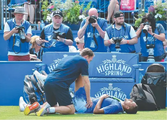 ?? Picture: AFP ?? Nick Kyrgios receives medical treatment after slipping against Donald Young in their first-round match at the ATP AEGON Championsh­ips.