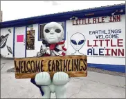  ??  ?? An alien-like statue displays a sign welcoming guests to the Little A’le’Inn restaurant and gift shop in Rachel, Nevada. The 10-room motel is one of few businesses in Rachel, a town of 54 residents.