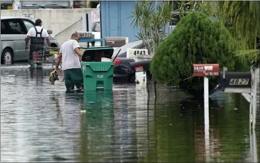  ?? THE ASSOCIATED PRESS PHOTOS ?? Residents clear debris from a flooded street in the Driftwood Acres Mobile Home Park, in the aftermath of Tropical Storm Eta, Nov. 10, in Davie, Fla.