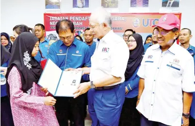  ?? -Gambar Bernama ?? NAJIB menyerahka­n sijil Kewarganeg­araan kepada Nur Azlina (kiri) ketika meninjau Jabatan Pendaftara­n Negara selepas Perasmian Pusat Transfomas­i Bandar (UTC) Tawau, Isnin. Turut hadir Ketua Menteri Sabah Tan Sri Musa Aman (kanan).