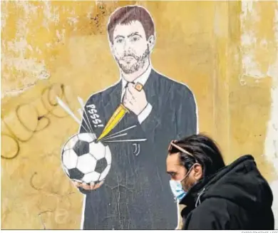  ?? FABIO FRUSTACI / EFE ?? Un ciudadano de Roma pasa ante un mural con Andrea Agnelli, pintado por el artista urbano Laika MCMLIV.