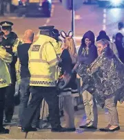  ?? [AP PHOTO] ?? Emergency services personnel speak to people outside Manchester Arena after 19 people were killed by a blast during an Ariana Grande concert Monday in Manchester, England.