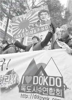 ?? — AFP photo ?? I LOVE DOKDO: A South Korean protester holds a banner showing a portrait of Japan’s Prime Minister Shinzo Abe (top) during an anti-Japan rally outside the Japanese embassy in Seoul.