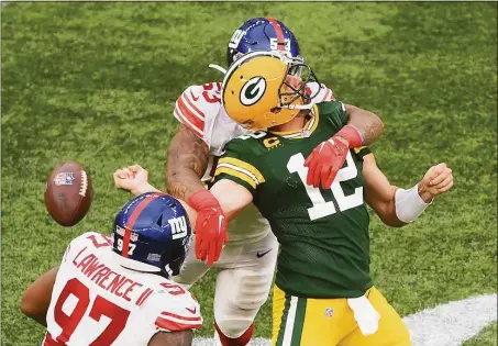  ?? Mike Hewitt / Getty Images ?? The Green Bay Packers’ Aaron Rodgers (12) is sacked by the New York Giants’ Oshane Ximines and fumbles the ball in the fourth quarter Sunday at Tottenham Hotspur Stadium in London.