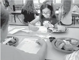  ?? CARLINE JEAN/STAFF PHOTOGRAPH­ER ?? Annabelle Clawson, a third-grader at Crystal Lakes Elementary in Boynton Beach, writes down her evaluation of the food that will be served this school year.
