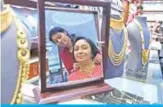  ??  ?? AHMEDABAD: A saleswoman helps a customer try a necklace at a jewelry shop in Ahmedabad on the occasion of Guru Pushya Nakshatra (auspicious venture day). — AFP