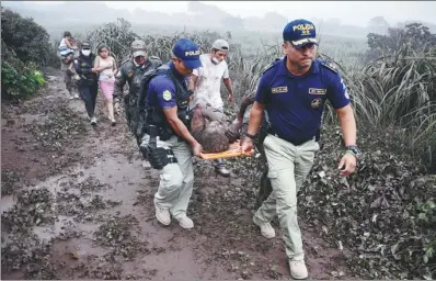  ?? NOE PEREZ / AGENCE FRANCE-PRESSE ?? Police officers carry a wounded man after the eruption of the Fuego Volcano, in El Rodeo village, Guatemala, on Sunday.