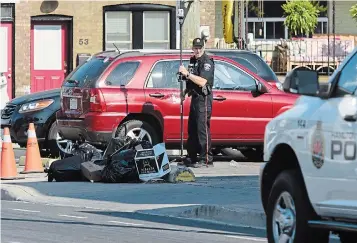  ?? JOHN RENNISON PHOTOS THE HAMILTON SPECTATOR ?? On Wednesday morning, a Hamilton police officer was surveying the area around where a shooting occurred at Cannon and Gage on Tuesday.