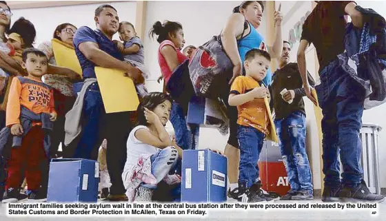  ?? AP ?? Immigrant families seeking asylum wait in line at the central bus station after they were processed and released by the United States Customs and Border Protection in McAllen, Texas on Friday.
