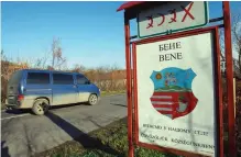  ??  ?? A car near a road sign of Bene village with inscriptio­ns in two languages, Ukrainian and Hungarian and village emblem not far from Beregove, a small town in western Ukraine. óAFP photos