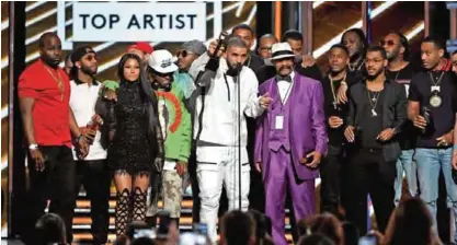  ??  ?? Rapper Drake (center) accepts the Top Artist award onstage with songwriter­s, producers and father Dennis Graham.