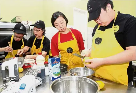  ??  ?? Never too many cooks: (From left) Jonathan Lee and mum Connie Koh mixing cake batter, while Teh and Lim Qi Han grate lemon zest at Bake with Dignity.