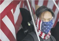  ??  ?? A protester wears an American flag scarf at yesterday’s rally