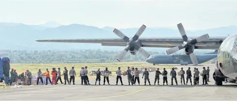  ?? AFP ?? Indonesian soldiers and policemen unload aid from a Hercules plane in Palu.