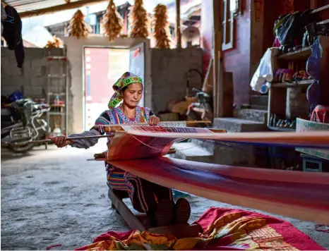  ??  ?? Una mujer Derung teje una manta en su casa en Dulongjian­g.