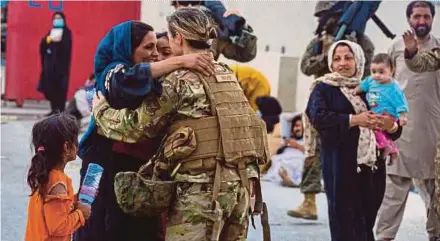  ?? AFP PIC ?? A United States airman with the Joint Task Force-Crisis Response embracing a woman after helping to reunite her family, at Hamid Karzai Internatio­nal Airport in Kabul on Friday.