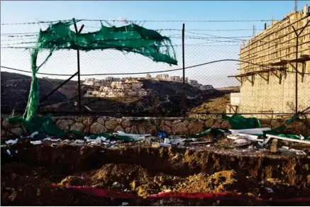 ?? DAVID VAAKNIN/THE WASHINGTON POST ?? Houses in the Jewish settlement of Efrat in the West Bank are seen in the distance through a fence at a constructi­on site on Friday.