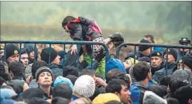  ??  ?? A Croatian police officer carries a child as migrants wait to enter Croatia from the Serbia-Croatia border, near the western Serbian village of Berkasovo on Monday. AFP