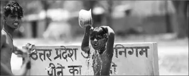  ??  ?? Indian boys bath at a drinking water tap on a hot day in Prayagraj, India. (Photo: The Guardian)