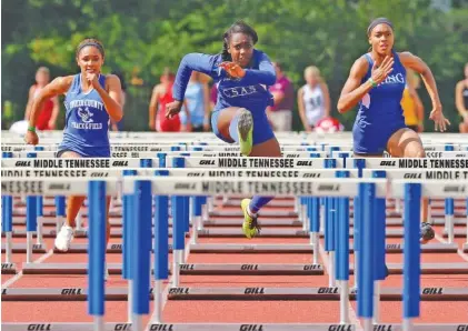  ?? STAFF PHOTO BY DOUG STRICKLAND ?? CSAS’s Lennex Walker, center, is on her way to winning the girls’ 100-meter hurdles, flanked by MLK’s Denia Hill-Tate, right, and Unicoi County’s Stephanie Wisse on Thursday in Murfreesbo­ro.