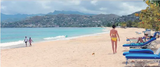  ?? DAVID MCFADDEN/THE ASSOCIATED PRESS FILES ?? Visitors walk on the white sand of the Grand Anse Beach in Grenada, one of the Caribbean island nations that is open for business as usual.