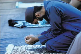  ?? Yalonda M. James / The Chronicle ?? Above: At Abdullah Anwar, nephew of Imam Tahir Anwar, prays at Masjid alMustafa mosque in San Jose. Left: Prayer shawls at Congregati­on Sherith Israel.