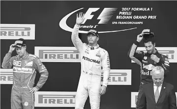  ??  ?? Lewis Hamilton (centre) celebrates on the podium next to second placed Sebastian Vettel (left) and third placed Daniel Ricciardo after the Belgian Formula One Grand Prix at the Spa-Francorcha­mps circuit in Spa in this Aug 27 file photo. — AFP photo