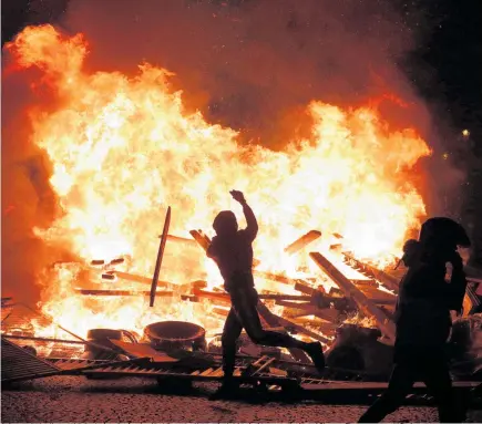  ?? PHOTO / AP ?? A demonstrat­or throws debris at a burning barricade while protesting against rising fuel taxes on the famed Champs Elysees avenue, in Paris.