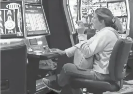  ?? AP FILES ASSOCIATED PRESS ?? A woman smokes while playing a slot machine at the Ocean Casino Resort in Atlantic City, N.J., in February. A new report suggests ending smoking in casinos will not result in significant financial harm to the businesses.