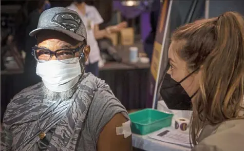  ?? Emily Matthews/Post-Gazette ?? Carlos Miyares, of West Brownsvill­e, talks to Jennifer Paliani, a pharmacist with UPMC Health Plan, after receiving a dose of the Moderna COVID-19 vaccine during a vaccinatio­n event on March 13 at Bethany Community Ministries in Homewood.