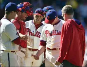  ?? DERIK HAMILTON — THE ASSOCIATED PRESS ?? Phillies starting pitcher Jeremy Hellickson, second from right, looks at his hand after a injury during the sixth inning against the Nationals, Sunday in Philadelph­ia. Hellickson left with what he called a cramp in his forearm, but did not seem to...