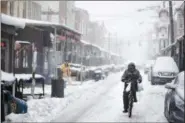  ?? MATT ROURKE — THE ASSOCIATED PRESS ?? A man rides his bicycle during a winter storm in the Italian Market neighborho­od of Philadelph­ia, Tuesday.