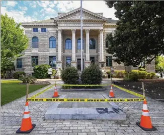  ?? PHOTOS BY JOHN AMIS / FOR THE AJC ?? An empty spot remains Friday in Decatur where an obelisk outside the Historic DeKalb Courthouse erected by the Daughters of the Confederac­y in 1908 was dismantled Thursday night. A crowd gathered to watch it lifted off its pedestal with a crane.