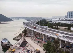  ??  ?? In this picture taken on November 29, 2017, a general view shows a section of the Hong Kong-Zhuhai-Macau Bridge (HKZMB) (center) that runs alongside the internatio­nal airport (right) in Hong Kong. Billed as the world's longest sea bridge connecting...