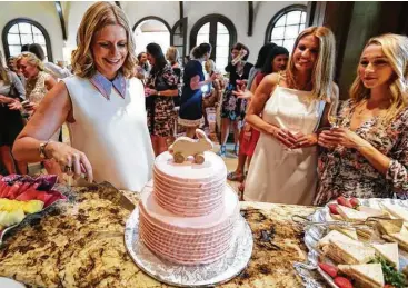  ?? Annie Mulligan photos ?? Valerie Dieterich slices into a strawberry cake during her baby shower.