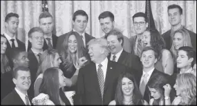  ??  ?? President Donald Trump looks over as a White House intern removes a piece of lint as they poses for a photo in the East Room of the White House.