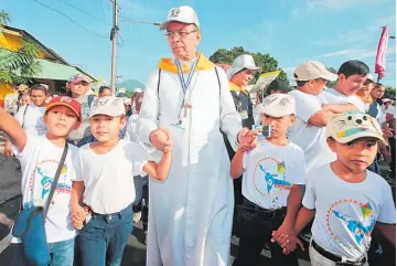  ??  ?? El cardenal Gregorio Rosa Chávez es acompañado por los niños que harían su recorrido en un tramo de la alameda Juan Pablo II. “Cero violencia, todo ternura” es el lema de los chicos.
