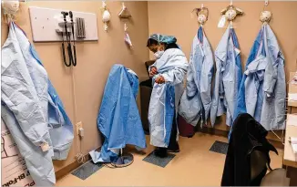  ?? BEN GRAY FOR THE ATLANTA JOURNAL- CONSTITUTI­ON ?? A nurse practition­er at Good Samaritan Health Center in northwest Atlanta dons her PPE before testing a patient for COVID- 19 in the center’s triage room Thursday.