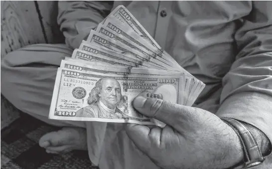  ?? REUTERS ?? A trader displays U.S. dollar banknotes at a currency exchange booth in Peshawar, Pakistan, Sept. 15, 2021.