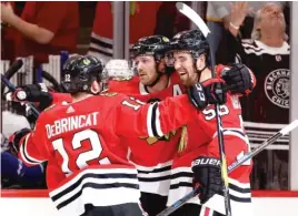  ?? JONATHAN DANIEL/GETTY IMAGES ?? Alex DeBrincat (from left) and Duncan Keith help Erik Gustafsson celebrate his tying goal late in the third period Monday at the United Center.