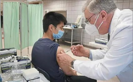  ?? Peter Diana/Post-Gazette ?? Gabriel Tran, a junior at Upper St Clair High School, gets a dose of the Pfizer COVID-19 vaccine from Dr. G. Alan Yeasted on Tuesday at the school.