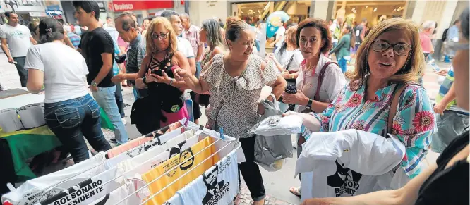  ?? WILTON JUNIOR/ESTADÃO ?? Rua Halfeld. Militantes pró-Bolsonaro estampam camisetas com o rosto do candidato, de graça, na Praça da Estação, em Juiz de Fora (MG), em frente ao local onde ele foi esfaqueado