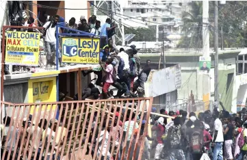  ??  ?? People loot shops in Delmas, a commune near Port-au-Prince, during protests against the rising price of fuel. — AFP photo