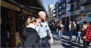  ?? FOTO ERNST VAN NORDE ?? Anja Christense­n, medarbejde­r i Waxies Pub, får en venlig bemærkning fra en betjent fra Østjylland­s Politi om, at folk skal huske at holde afstand.