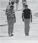  ?? BILL STREICHER/USA TODAY SPORTS ?? Dustin Johnson, left, and Matt Kuchar walk up the eight fairway during the first round foursomes match of The President's Cup Thursday at Liberty National Golf Course in Jersey City, N.J.