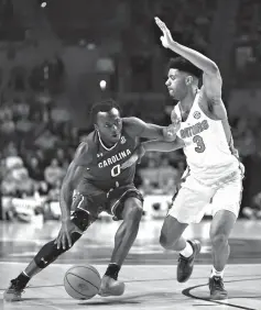  ?? Associated Press ?? ■ South Carolina guard David Beatty (0) dribbles against the defense by Florida guard Jalen Hudson (3) during the first half of an NCAA college basketball game Wednesday in Gainesvill­e, Fla.