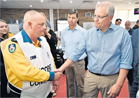  ??  ?? Australian Prime Minister Scott Morrison, right, greets a New South Wales Rural Fire Service officer during a briefing at the Wollondill­y Emergency Control Centre in Sydney